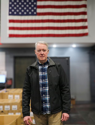 Greg Goode standing in front of an American Flag